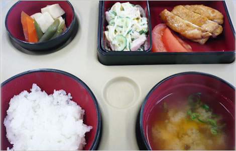 介護施設の食事風景。赤い器で盛り付けられた栄養バランスの良い日本食。